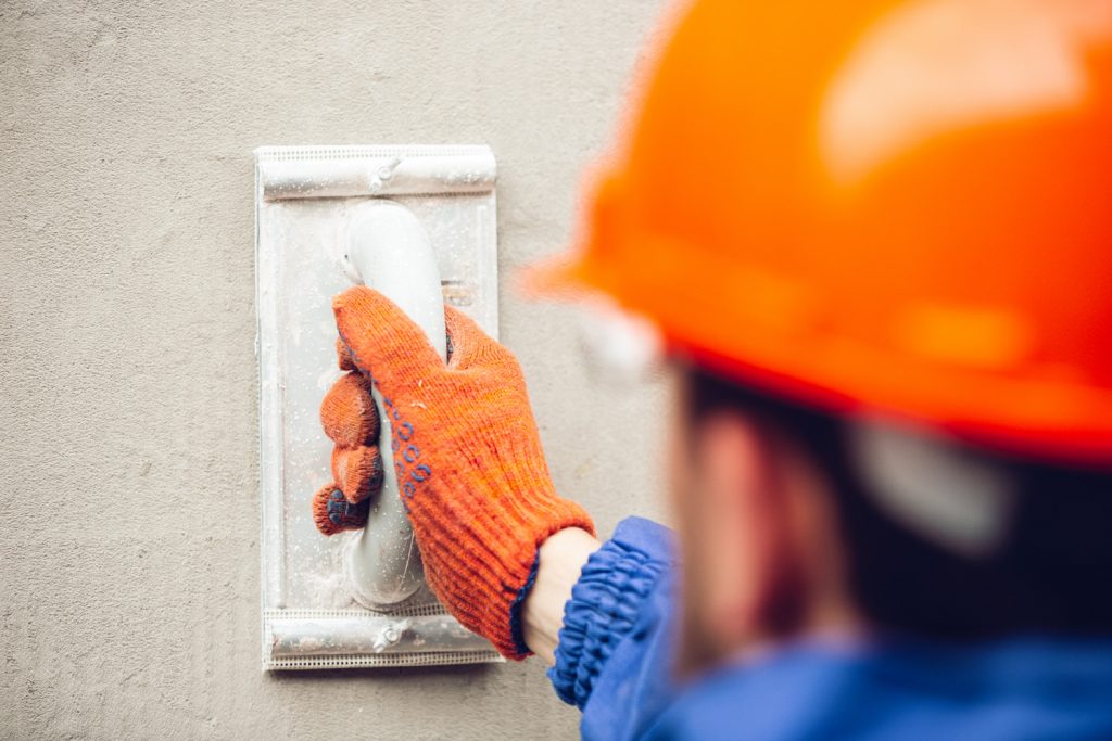 Worker in orange helmet plastering the wall