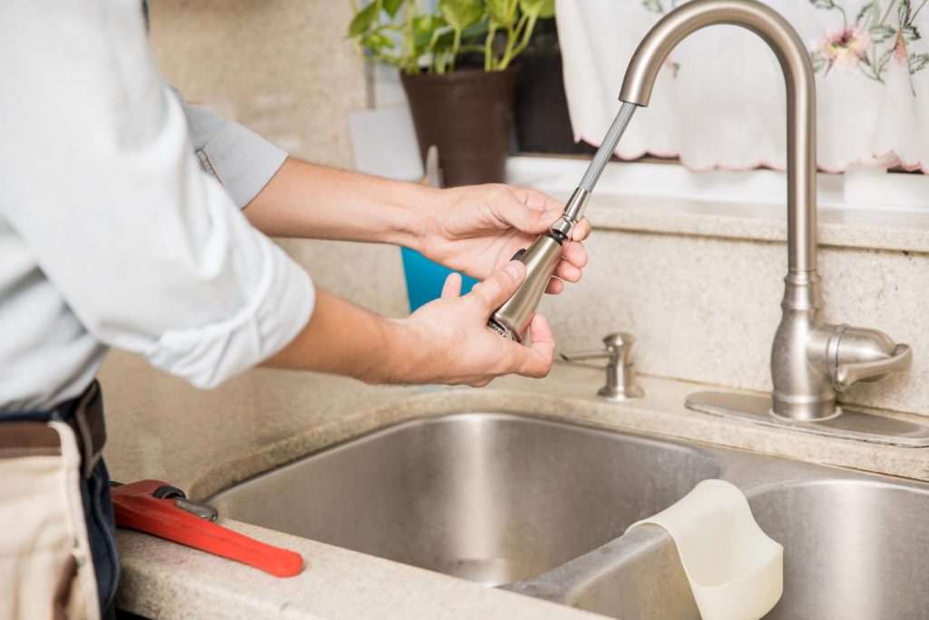 Young man repairing kitchen faucet